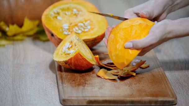 木製キッチン テーブルにカボチャの清掃の女性 オレンジのカボチャの部分を切断する準備をして男性 — ストック動画