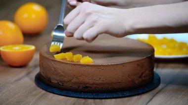 Kadın el çikolatalı mousse kek turuncu kesimleri ile dekore edilmiştir.