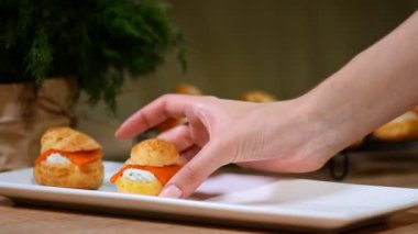 Eller profiterol somon ile beyaz bir levha koymak.