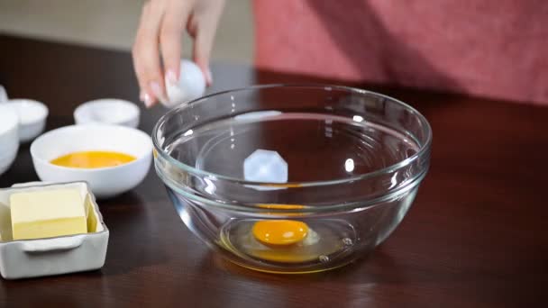 Femme main casse oeuf de poulet dans un bol. Oeuf de poulet tombe dans un bol en verre . — Video