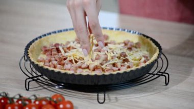 Aşçının eli turtanın üstüne peynir koyuyor.