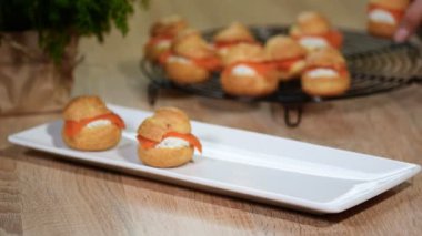 Eller profiterol somon ile beyaz bir levha koymak.