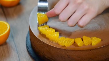 Kadın el çikolatalı mousse kek turuncu kesimleri ile dekore edilmiştir.