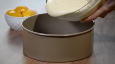 Bir kadın hamur bir pişirme çanağı dökülen.