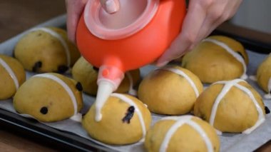 Çiğ çiğ buns. Ev yapımı Paskalya geleneksel sıcak çapraz kagit üzerinde buns pişirmeye hazır. Eller bir çapraz yapmak.
