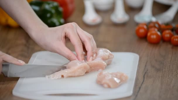 Femme chef coupe de la viande de poulet crue sur un plateau en bois . — Video