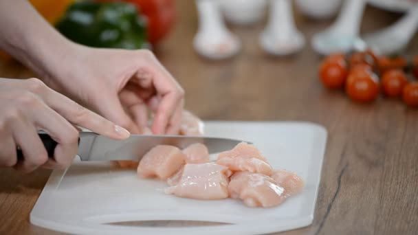 Mão feminina corta um pedaço de filé de frango . — Vídeo de Stock