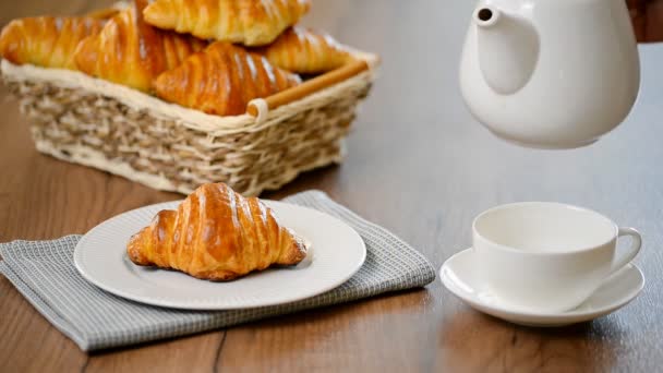 Croissant s čajem. Snídaně koncept. Nalévání čaje v šálku čaje