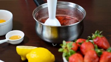Yemek sosu, reçeli, çilek lezzetli meyve ile daldırma blender paslanmaz çelik tencerede öğütme portre.