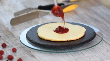 Kremayı katmanlı kekin üzerine süren şekerleme. Böğürtlenli kek yapma süreci.