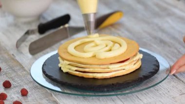 Kremayı katmanlı kekin üzerine süren şekerleme. Böğürtlenli kek yapma süreci.