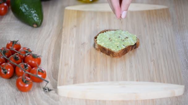 Авокадо тост з насінням льону на дерев'яному фоні . — стокове відео