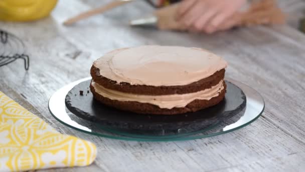 Crema que se aprieta en el pastel de chocolate. Apretando la crema en el pastel . — Vídeos de Stock