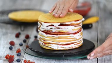 Kadın pasta şefi nin elleri katmanları lezzetli kek yapma, döner kek standı kullanarak krem şanti ve berry reçel, sol closeup çekim izleme.