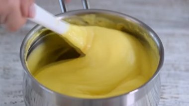 Kadın tencerede krema karıştırıyor..