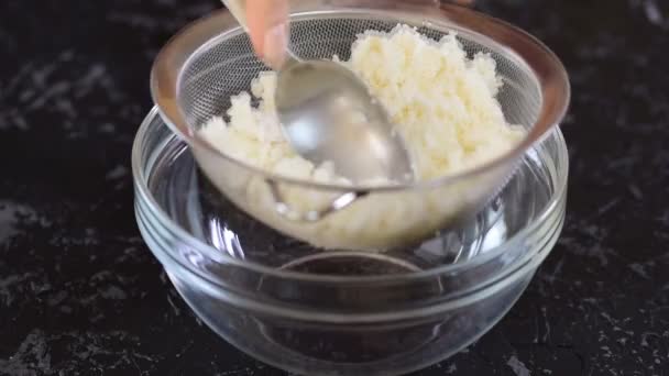 Жінка-пекарня протирає сир через сито . — стокове відео
