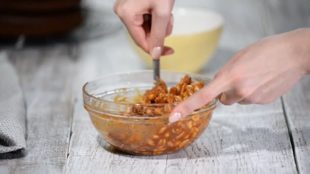 Cocinero revuelva los cacahuetes con salsa de caramelo en un tazón de vidrio . — Vídeo de stock