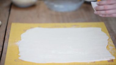 Fırının masasındaki büyük hamur tabakası, fırçayla kayganlaştırıyor..