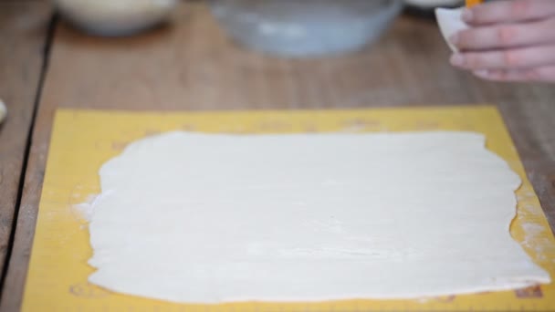 Duża warstwa ciasta na stole w piekarni, smaruje pędzlem. — Wideo stockowe