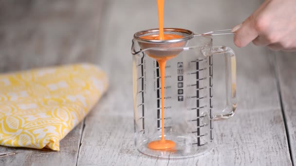 Woman sieve the mix of mirror glaze into a large jug to remove any excess bubbles. — Stock Video