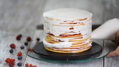 Aşçı kadın tarafından krem şanti pişmiş katmanlı pasta süsleme.