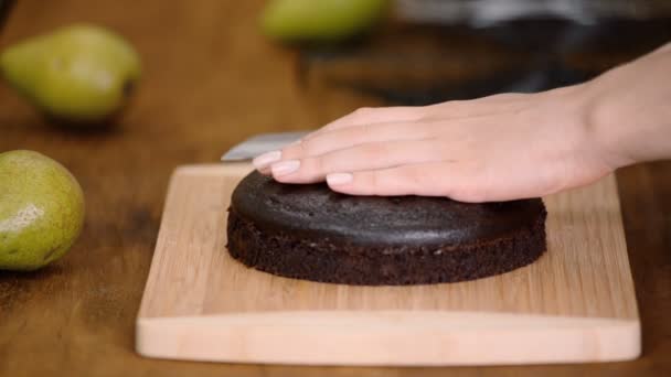 Banketbakker is het snijden van chocolade spons cake op schijfjes met grote mes. — Stockvideo