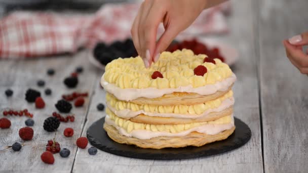Confectioner girl pone bayas de verano en un pastel de capa cremosa. Mujer preparando un pastel con crema y bayas . — Vídeos de Stock