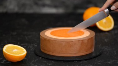 Kadın mutfak bıçağıyla portakallı kremalı pasta kesiyor..