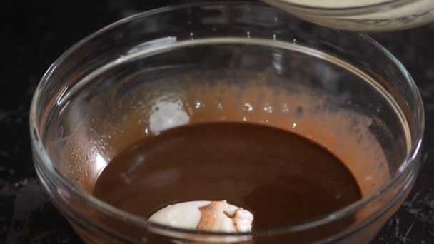 Frau gießt Schlagsahne in eine Schüssel mit Schokolade. Herstellung von Schokoladenmousse. — Stockvideo