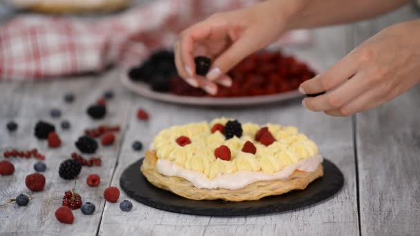 과자먹는 여자 애가 여름 베리를 크림 층의 케이크 위에 올려 놓는 거야. 크림 과 딸기로 케이크를 만드는 여자. — 비디오