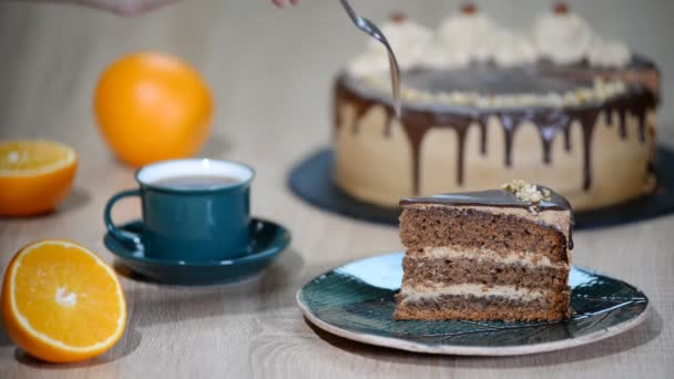 porce dortu s čokoládovou polevou a pomerančem na talíři.