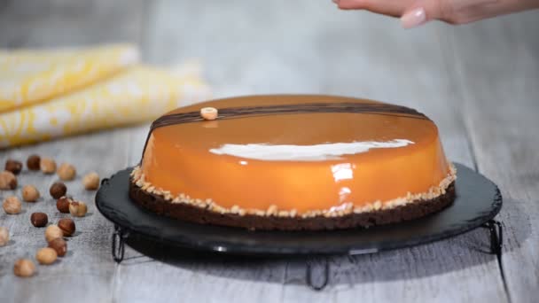 Konditorin verziert Haselnuss-Karamell-Mousse-Kuchen mit Spiegelglasur. — Stockvideo