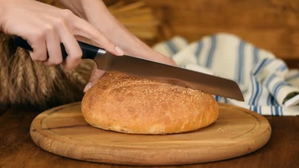 Жінка ріже хліб на дерев'яній дошці. Випічка. Виробництво хліба . — стокове відео