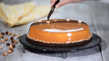 Şekerci kadın Fındık Karamelli Kremalı Kek 'i Ayna Şekeri ile süslüyor.