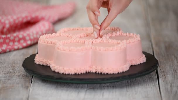 Pastry chef is decorates a pink cake in the shape of a flower. Series. — Stock Video