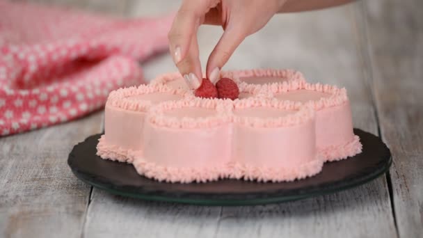 Pasticcere è decora una torta rosa a forma di fiore con lamponi freschi. Serie. . — Video Stock