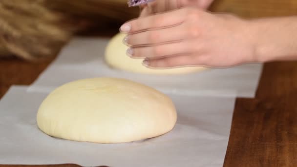 Beker przygotowuje chleb do pieca. Kobieta szczotka stopione masło na surowym chlebie. — Wideo stockowe