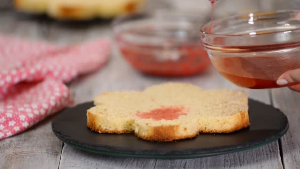 Inzuppare lo strato di torta di spugna con sciroppo. Pasticcere sta facendo una torta rosa a forma di fiore . — Video Stock