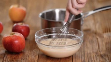 Kadın elleri cam kasede sıvı karışımı çırpıyor..