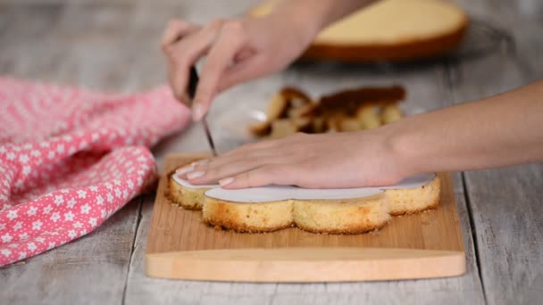 La mano femenina está cortando forma de flor de la torta de esponja . — Vídeos de Stock