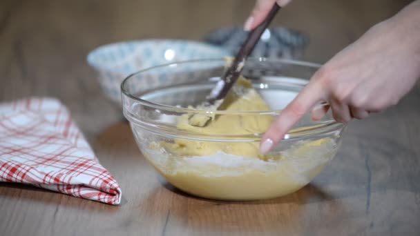 Je prépare un dessert. Une femme ajoute des pépites de chocolat noir à un contenant avec de la pâte. Remue un fouet . — Video