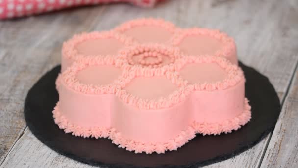 Mãos femininas cortar o bolo com creme rosa na forma de uma flor . — Vídeo de Stock