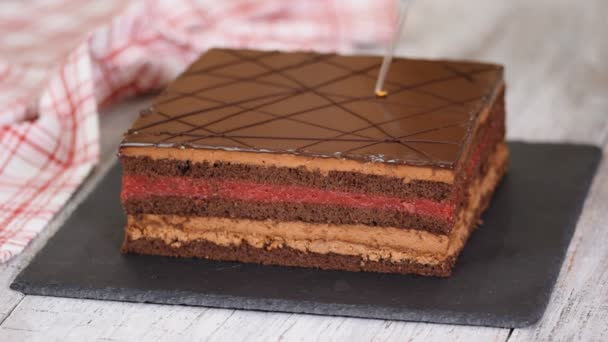 Primer plano de las manos de un chef de pastelería decora pastel de chocolate con pan de oro . — Vídeo de stock