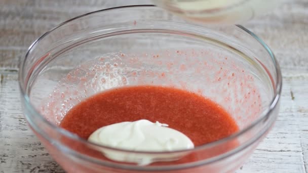 Erdbeermousse für Kuchen machen. Weibliche Hände geben Schlagsahne in Erdbeermischung. — Stockvideo