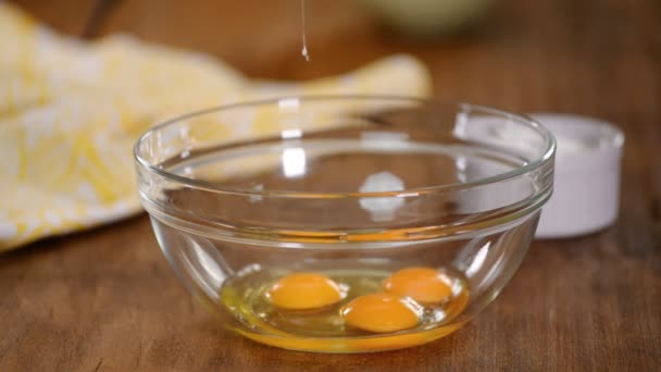 Close up of woman standing at kitchen table pouring sugar into deep plate with eggs then whisks eggs with a mixer. — ストック動画