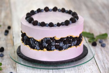 Böğürtlen, böğürtlen ve yaban mersiniyle süslenmiş mor güzel pasta. Hassas tatlı masası kavramı.