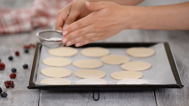 Un panadero usa un tamizador para espolvorear azúcar en polvo sobre la masa de hojaldre. Haciendo francesa Mille Feuille en la cocina . — Vídeo de stock