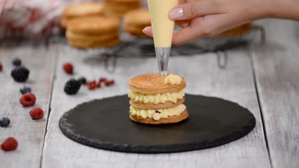 Banketbakker maakt French Mille Feuille met vla en bessen. Frans dessert millefeuille van bladerdeeg en vla crème. — Stockvideo