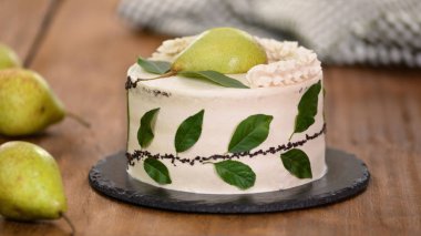Cream cake with decorated with fresh pear and green leaves.