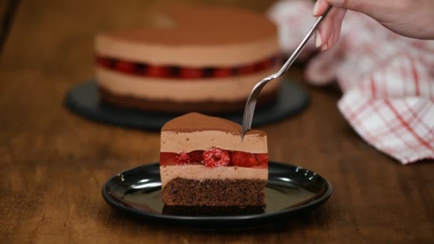 Woman eating piece of delicious chocolate mousse cake with raspberries jelly. — Stock Video